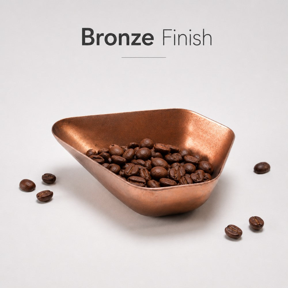 Bronze bowl filled with coffee beans on a light gray background