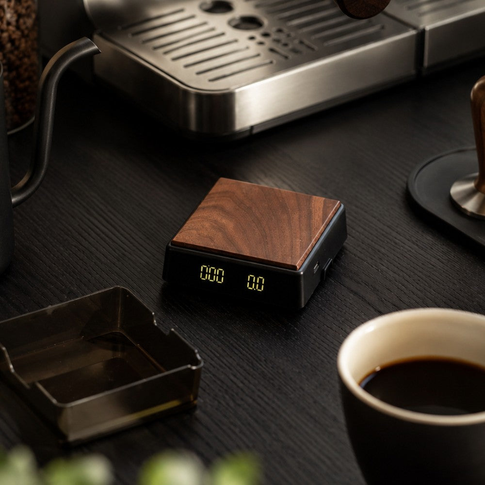 Mini espresso scale beside coffee cup and espresso machine