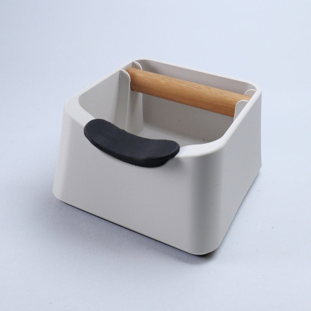 KNOCDIC The Pod 3-in-1 espresso knock box and tamping station in matte white featuring an integrated carbon fibre portafilter stand and oak bar.