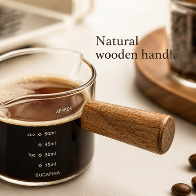 Natural wooden handle detail on glass espresso measuring cup
