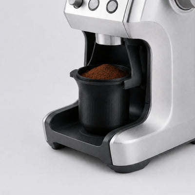 KNOCDIC 54mm espresso dosing cup with grinder activation tab locked into a Sage Barista Express grinder cradle.