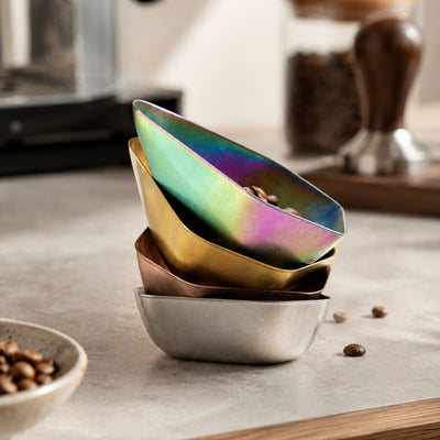 Stack of colorful stainless steel bowls on a kitchen counter with coffee beans.