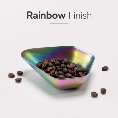 Triangular bowl with rainbow finish filled with coffee beans on a light gray background