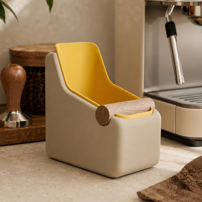 Matte yellow and desert tan espresso knock box in a kitchen setting with coffee equipment.