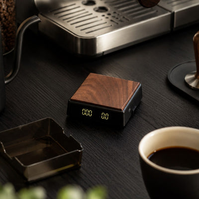 Mini espresso scale beside coffee cup and espresso machine