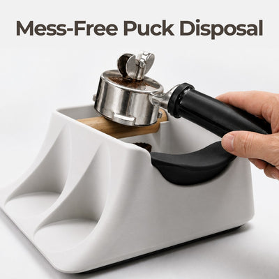 Close-up of a barista knocking out a spent espresso coffee puck into the matte white KNOCDIC knock box.