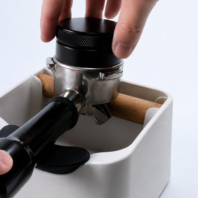 Hand using a coffee tamper on a white background