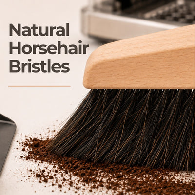 Cleaning brush with natural horsehair bristles cleaning coffee grounds on a light background.