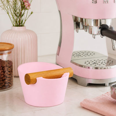 Matte pink customisable coffee knock box sitting next to a matching pastel pink home espresso machine.