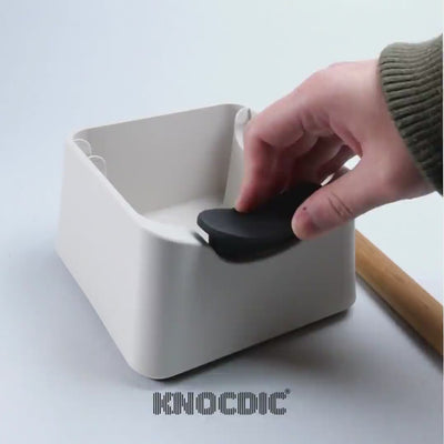 KNOCDIC The Pod 3-in-1 espresso knock box and tamping station in matte white featuring an integrated carbon fibre portafilter stand and oak bar.