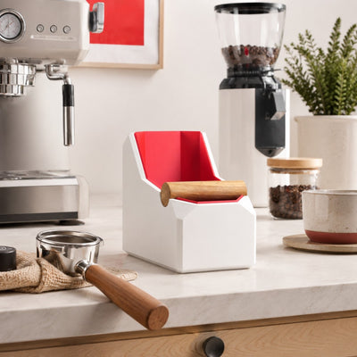 Matte white slim rectangular espresso knock box sitting neatly in a tight gap on a kitchen counter coffee bar.