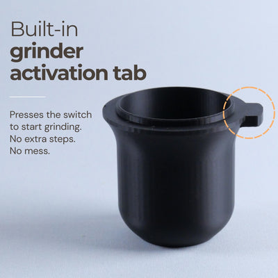 Close-up of a matte black 54mm espresso dosing cup showing the built-in grinder activation tab.