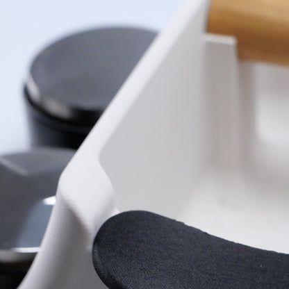 Close-up of a white kncok box with a wooden knock bar and black stabiliser in blurred background