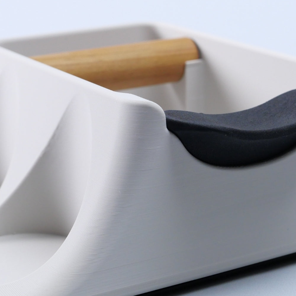 off white coffee tray with wooden bar, and black object on a light blue background